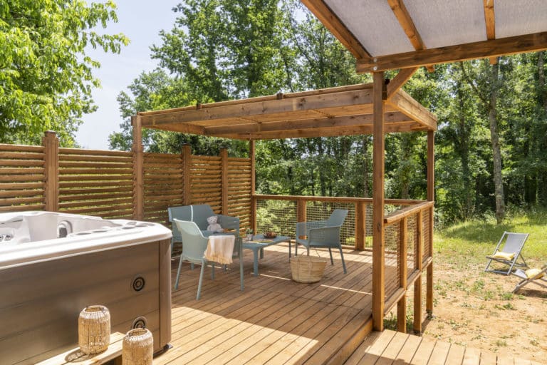 Terrasse en bois avec jacuzzi et fauteuils.