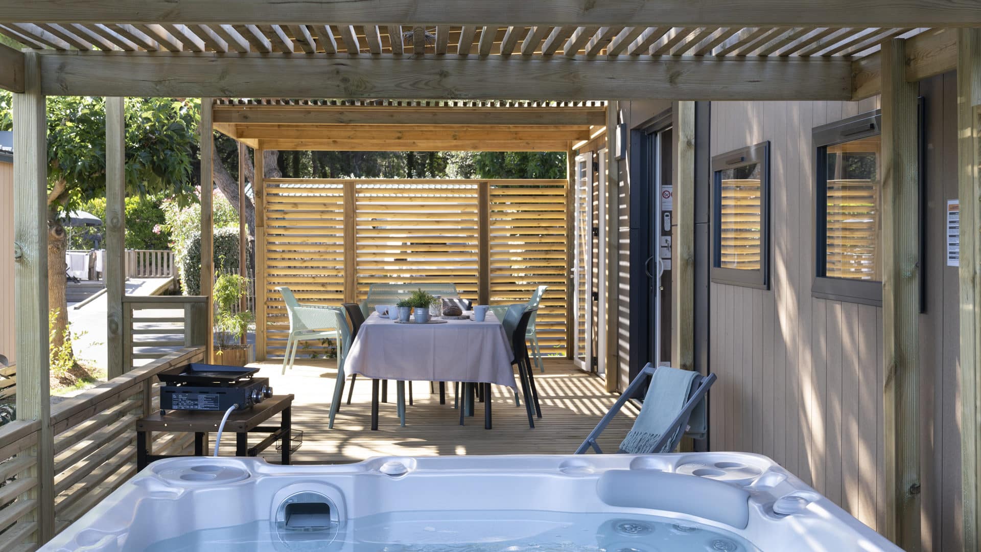 Houten terras met jacuzzi en gedekte tafel.